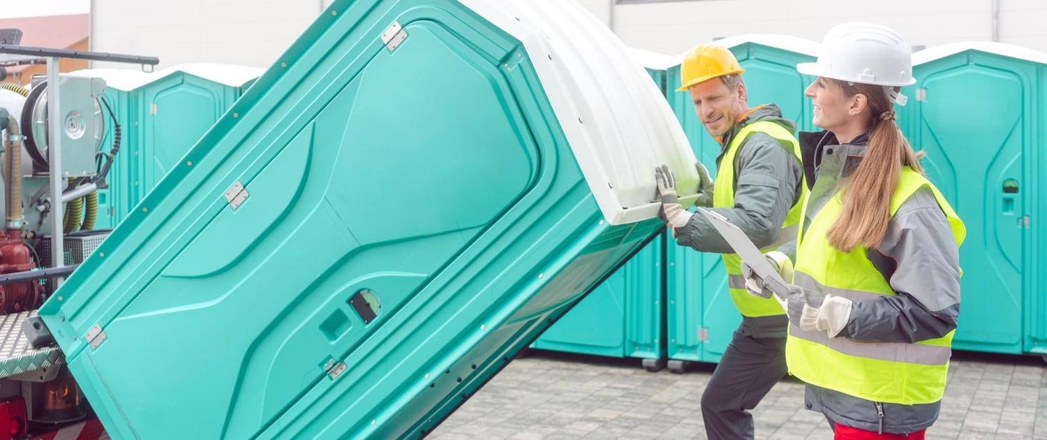 Two workers transporting portable toilet