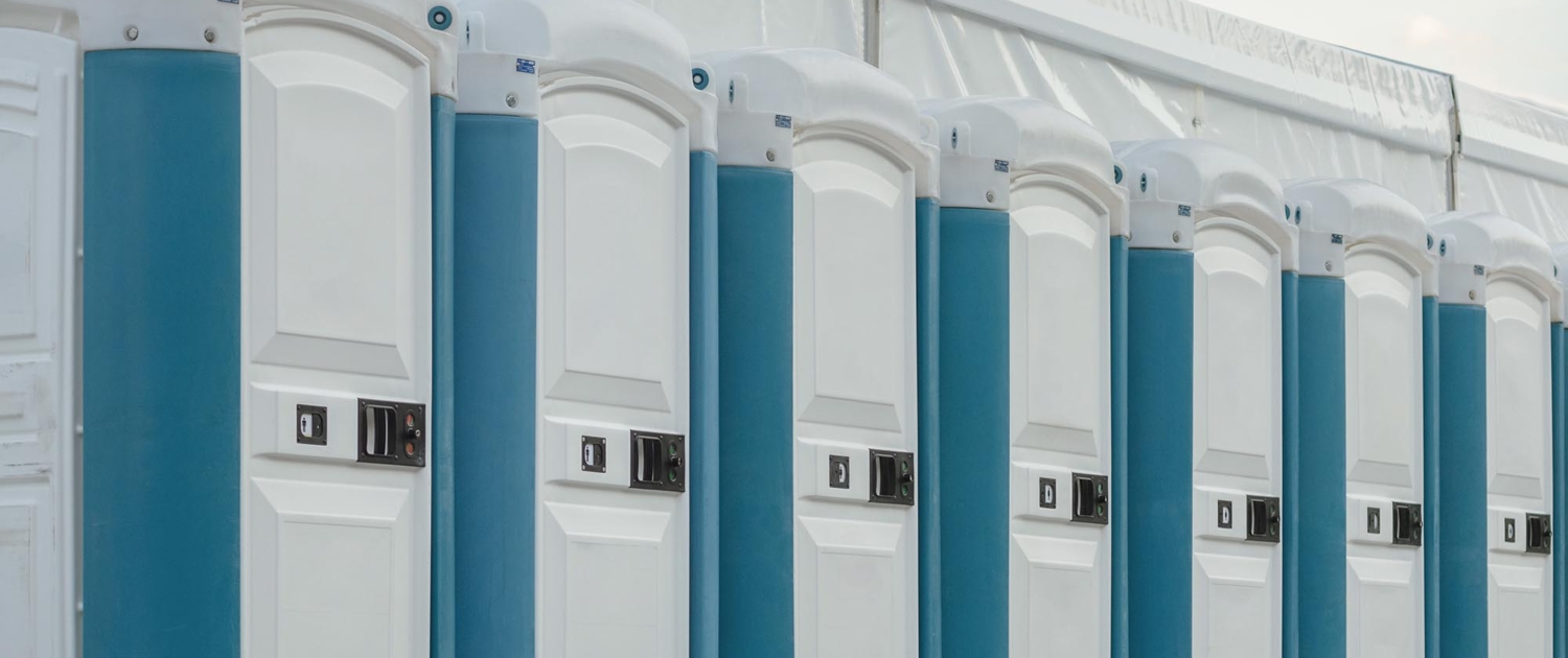 A row of several clean white and blue porta potties