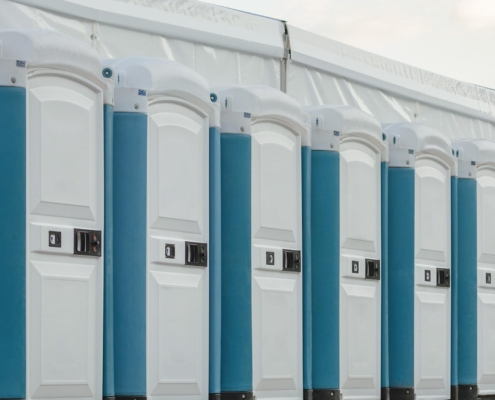 A row of several clean white and blue porta potties